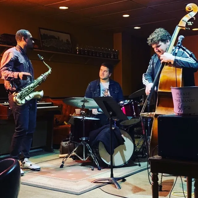 A saxophone, drums and upright bass trio playing live in the Bar Lounge