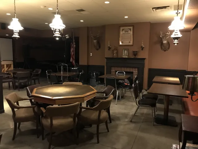 Card table and dark wood seating under wall sconces