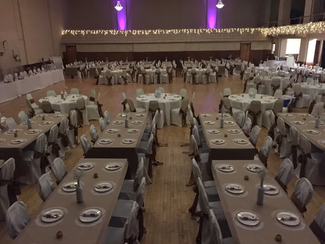 Long tables set with place settings under purple uplighting in the Grand Hall