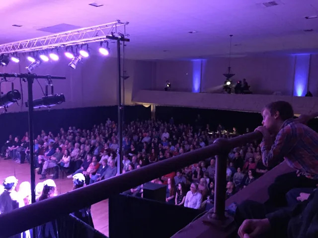 A full house watching a performance from the floor and balcony of the Grand Hall