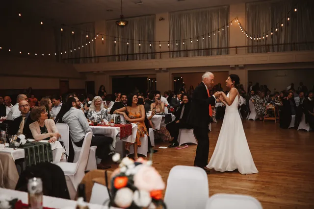 A father and daughter dancing while seated guests watch