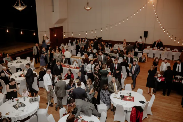 Round tables set with white linens across the Grand Hall for a formal gala