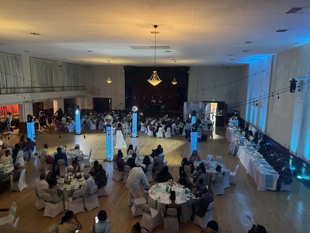 A full wedding reception in the Grand Hall with blue uplighting, lit columns and white chair covers