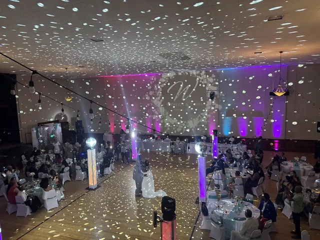 The Grand Hall with pink and purple uplighting, a projected monogram and mirror ball light across the ceiling