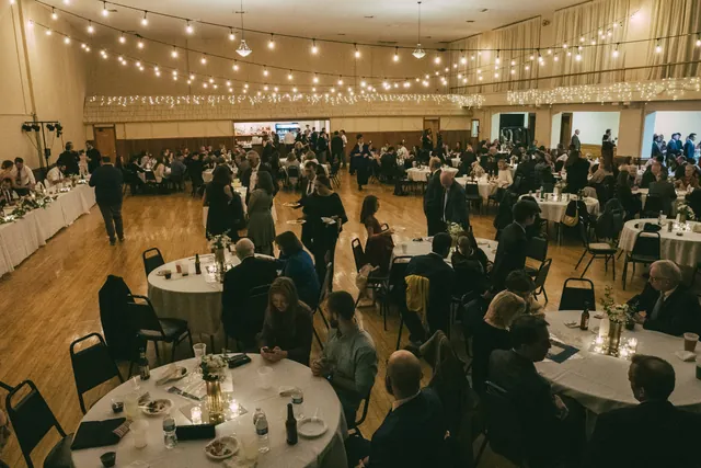 Round tables set for a reception with string lights overhead