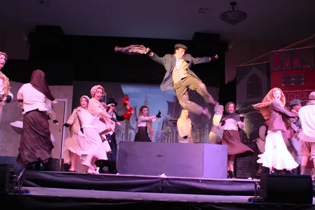 Performers on the stage at the end of the Grand Hall during a theatre production