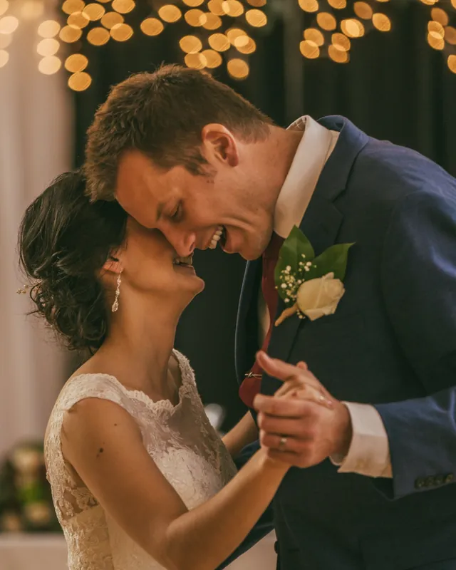 A bride and groom in a close portrait under warm bokeh lights