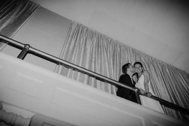 Black and white photograph of a couple embracing on the stairwell landing